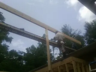 Carpenter setting a ridge beam over a new addition frame — Ice Dam Removal by Roofing Brothers in Haslet