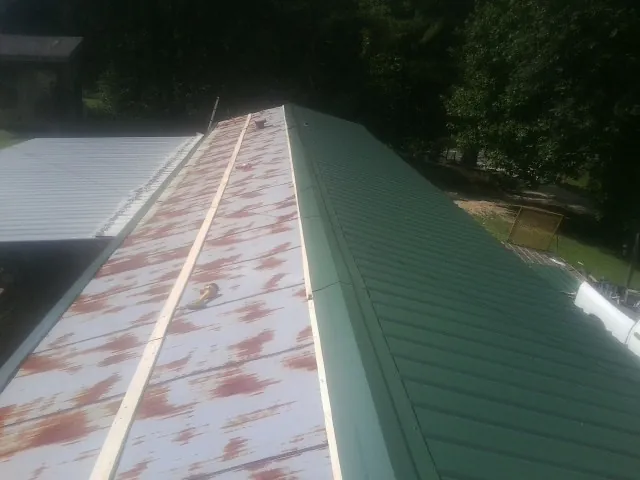 Old rusted panels beside newly installed green metal roofing — Wind Damage Roof Repair by Roofing Brothers in Haslet