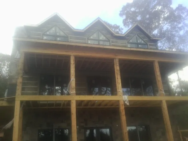 Dormers and porch framing on a large log home under construction — Roof Coating work by our crew in Haslet