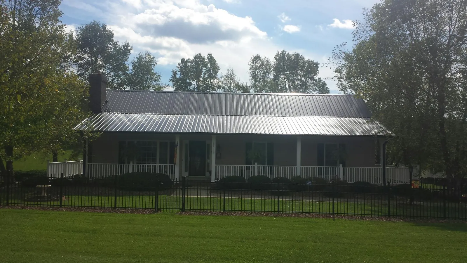 Gray metal roof on a brick ranch with a full width front porch — Gutter Guard Installation work by our crew in Haslet