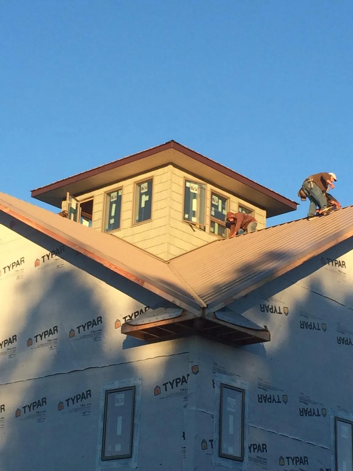 Roofers working around a rooftop cupola on a new metal roof at sunset — Roof Waterproofing in Haslet by Roofing Brothers